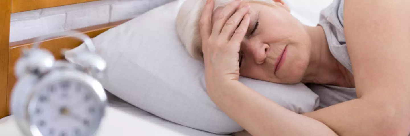 Frau mittleren Alters liegt schlaflos im Bett