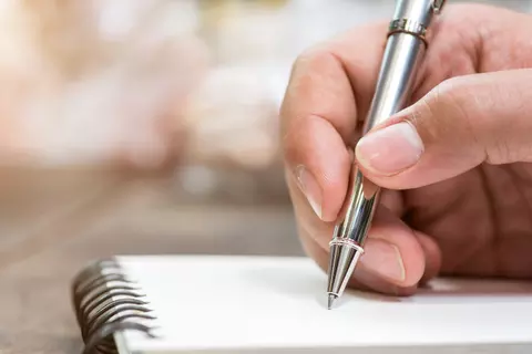 Hand hält einen Stift und schreibt