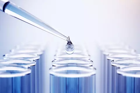 Pipette die eine Flüssigkeit in Reagenzgläser tropft