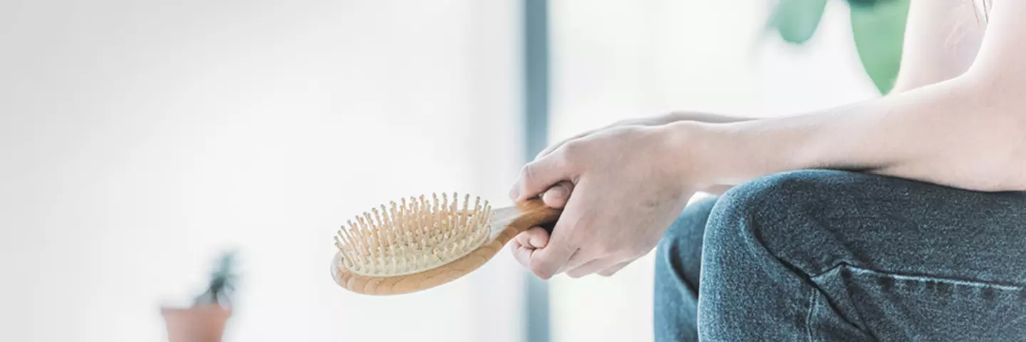 Hände einer Frau, die eine Haarbürste halten