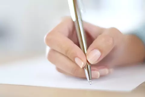Hand schreibt auf Papier